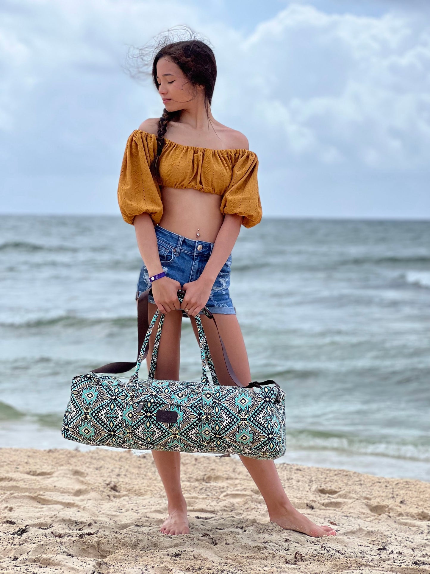 girl holding majestic yoga duffle bag at beach